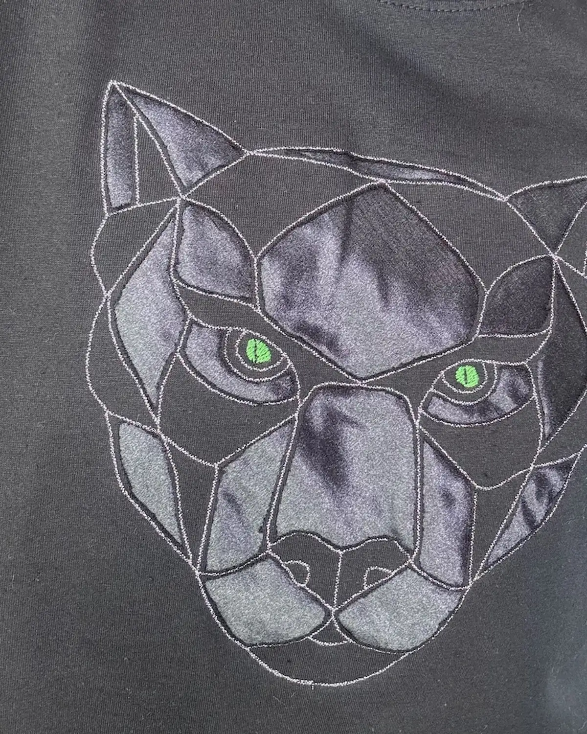 Black satin Monolit Panther pillow cover, the panther motif machine-embroidered into the fabric and held by tensioned thread.