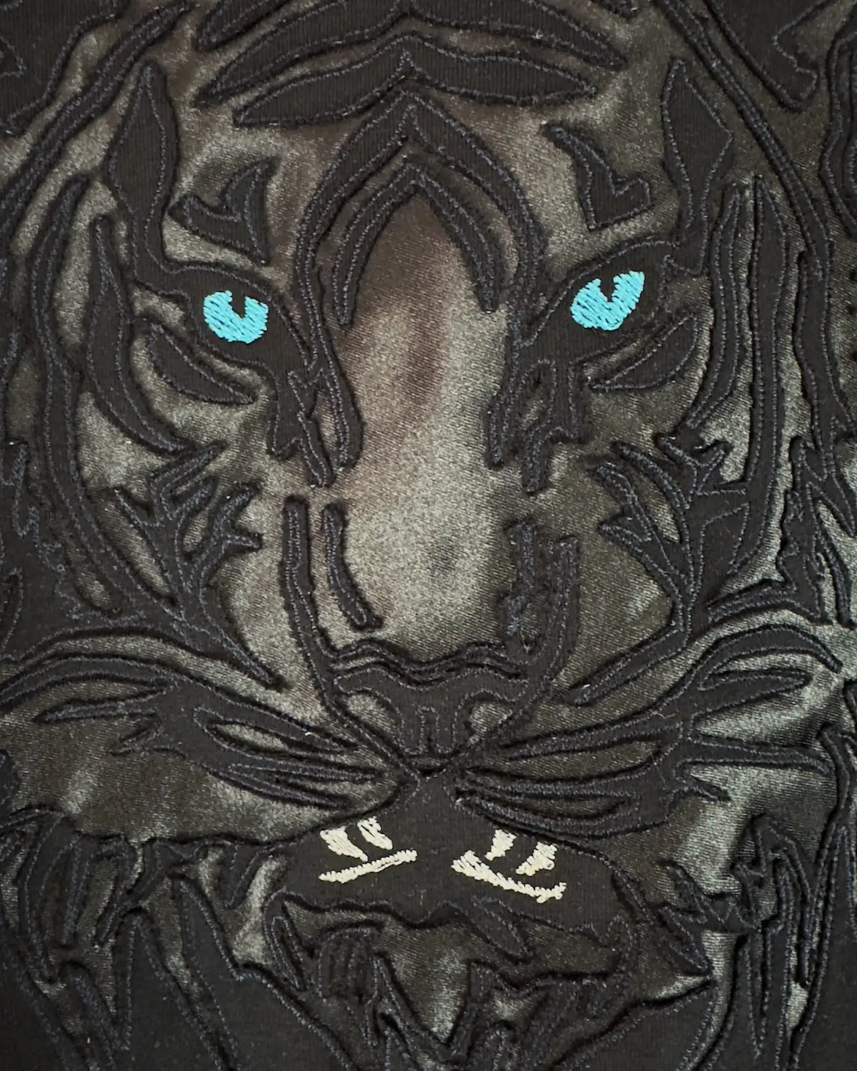 Black satin Monolit Tiger pillow cover, the tiger motif machine-embroidered into the fabric and held by tensioned thread.